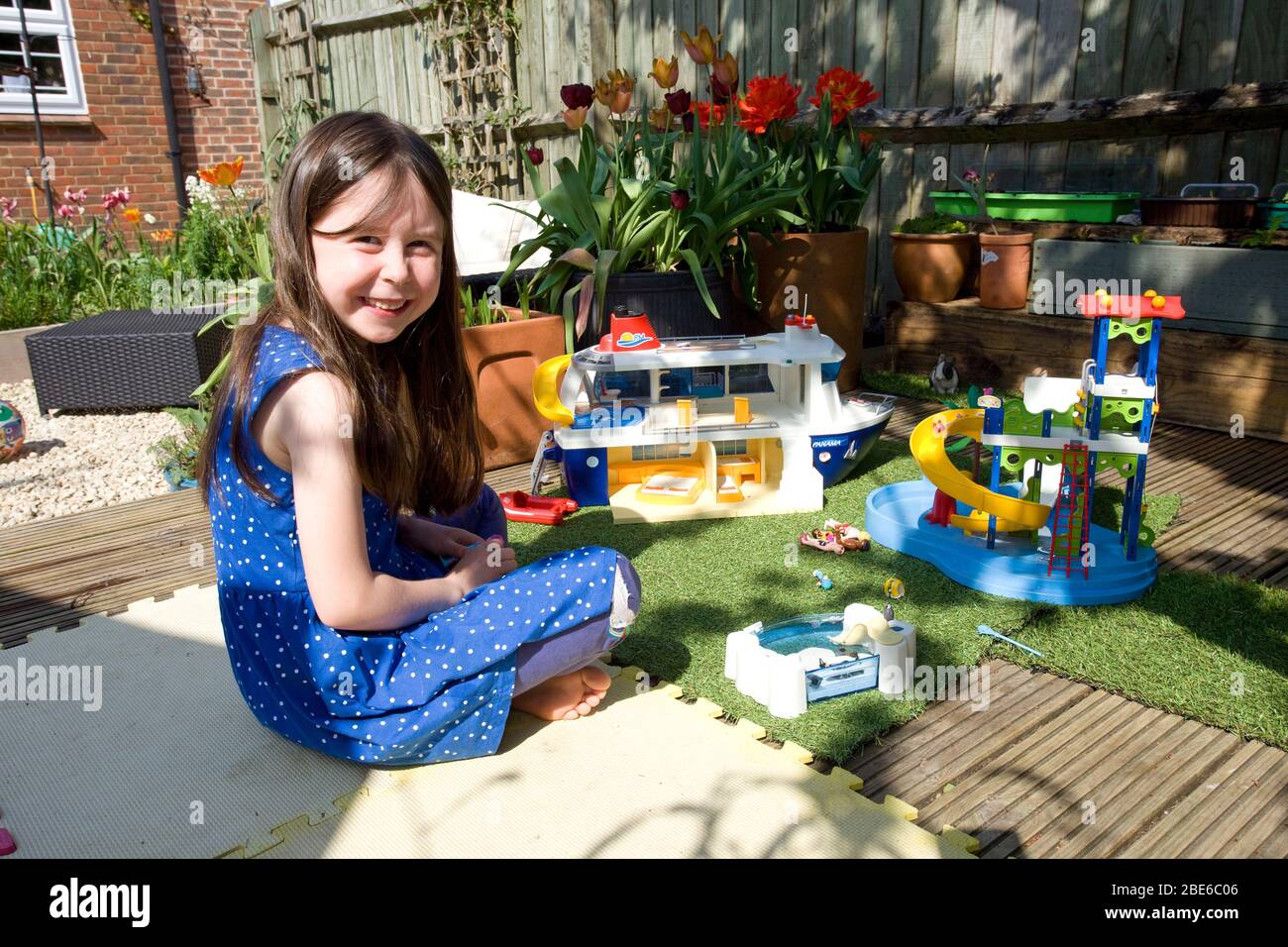 Junges Mädchen spielt mit playmobil im Garten Stockfoto