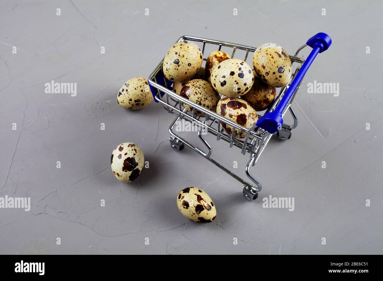 Wachteln Sie Eier in einem Wagen aus einem Supermarkt auf einem Betonhintergrund Stockfoto