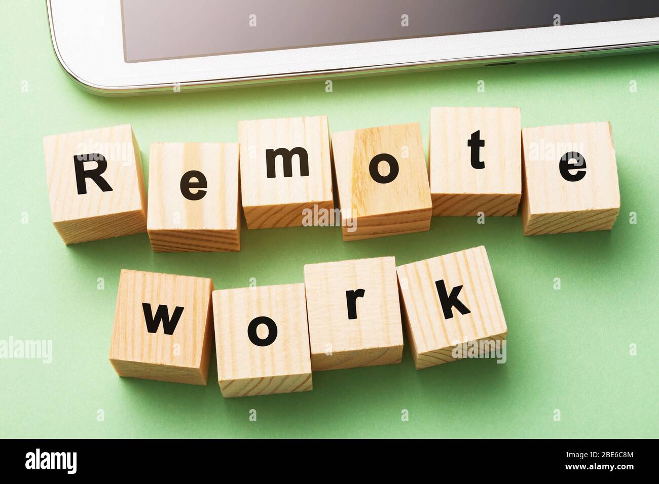 Holzwürfel mit Text und Tafel auf grünem Hintergrund. Remote Work-Konzept Sperren Stockfoto