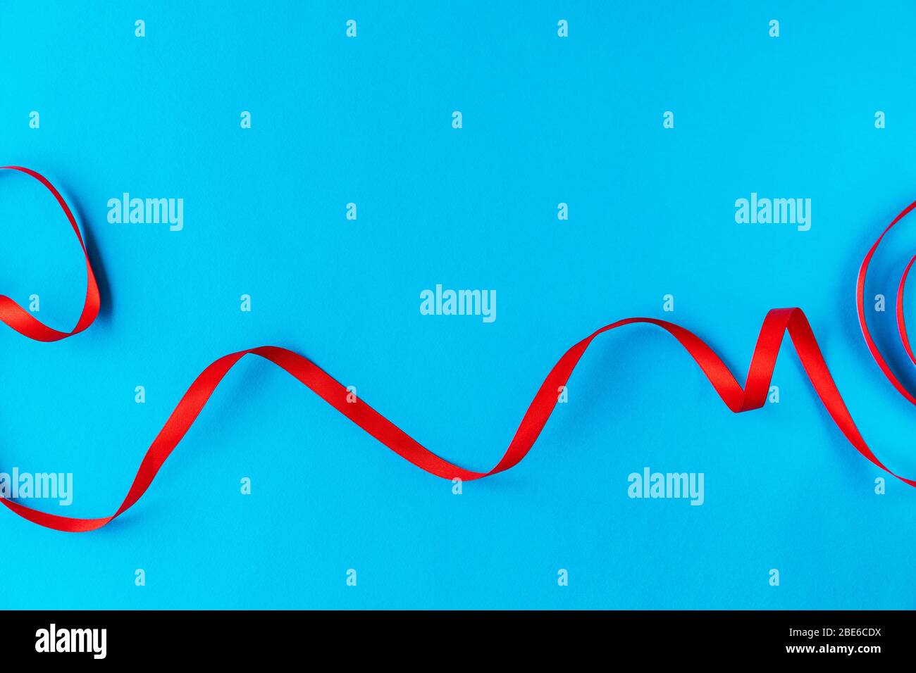 Gewelltes rotes Band auf blauem Hintergrund. Eine gute Idee für eine Urlaubskarte oder Hintergrund für Text, wie ein Computertapete oder ein Bildschirmschoner auf Ihrem Handy Stockfoto