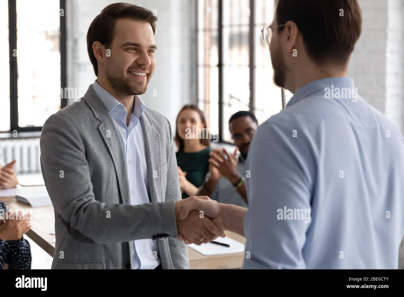 Der männliche Chef schüttelt die Hand des Mitarbeiters, der zur Jobförderung gratuliert Stockfoto