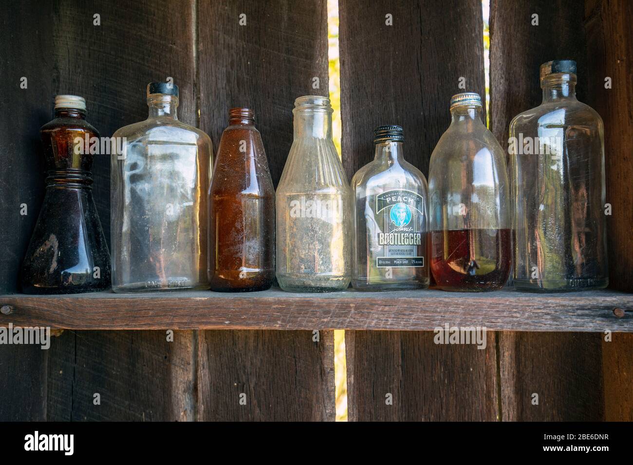 Alte verwitterte Glasflaschen Reihen sich in einer Reihe auf einem Holzregal auf - Penrose, North Carolina, USA Stockfoto