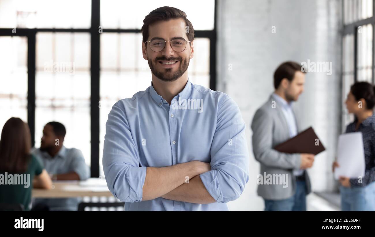 Lächelnder männlicher CEO posiert allein im modernen Büro Stockfoto