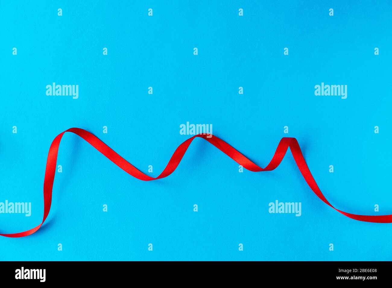 Gewelltes rotes Band auf blauem Hintergrund. Eine gute Idee für eine Urlaubskarte oder Hintergrund für Text, wie ein Computertapete oder ein Bildschirmschoner auf Ihrem Handy Stockfoto