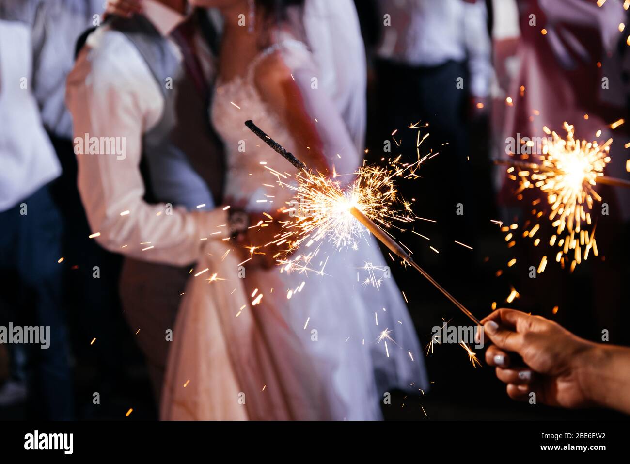 Funker in den Händen einer Hochzeit - Braut, Bräutigam und Gäste mit Licht Stockfoto