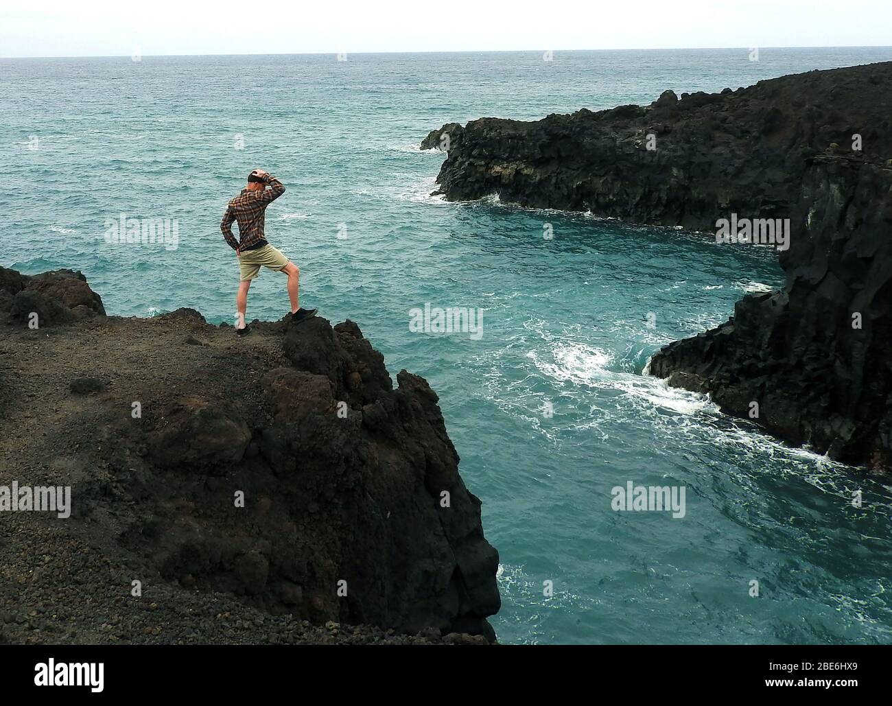 Ein Mann steht auf der Klippe bei Los Hervideros, Timanfaya, vulkanischer Nationalpark, Lanzarote, Kanarische Inseln, Spanien - Januar 2020. Stockfoto