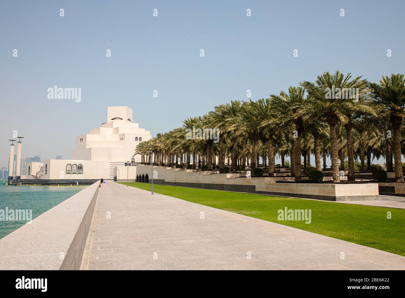 Blick auf das weiße Museum für Islamische Kunst in Doha City in Katar mit persischem Golf Wasser Hintergrund und rohen Palmen Stockfoto