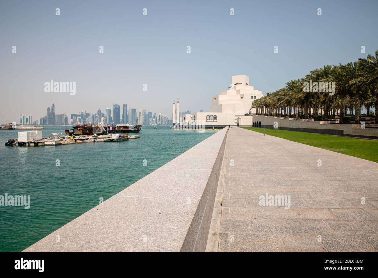 Blick auf das weiße Museum für Islamische Kunst in Doha City in Katar mit persischem Golf Wasser Hintergrund und rohen Palmen Stockfoto