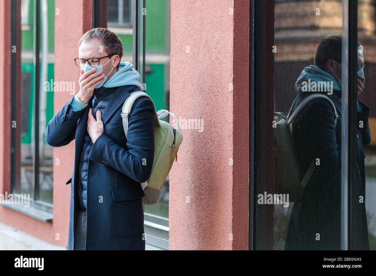 Mann in Brille krank fühlen im Freien, Husten, Tragen einer Schutzmaske gegen übertragbare Infektionskrankheiten und Schutz vor Viren - covid Stockfoto