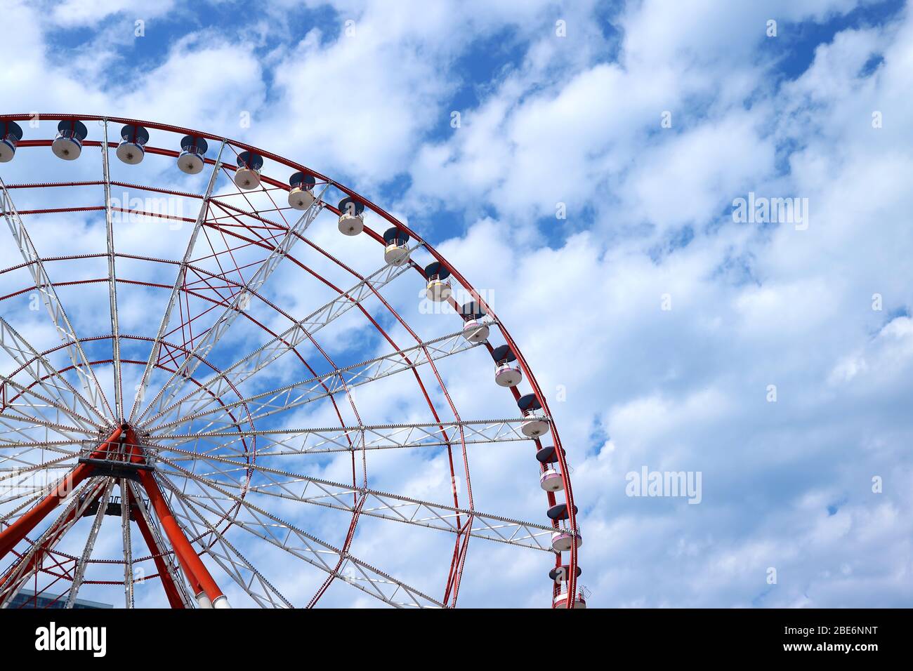 Rotes und weißes Riesenrad gegen blauen und wolkigen Himmel mit Kopierraum Stockfoto