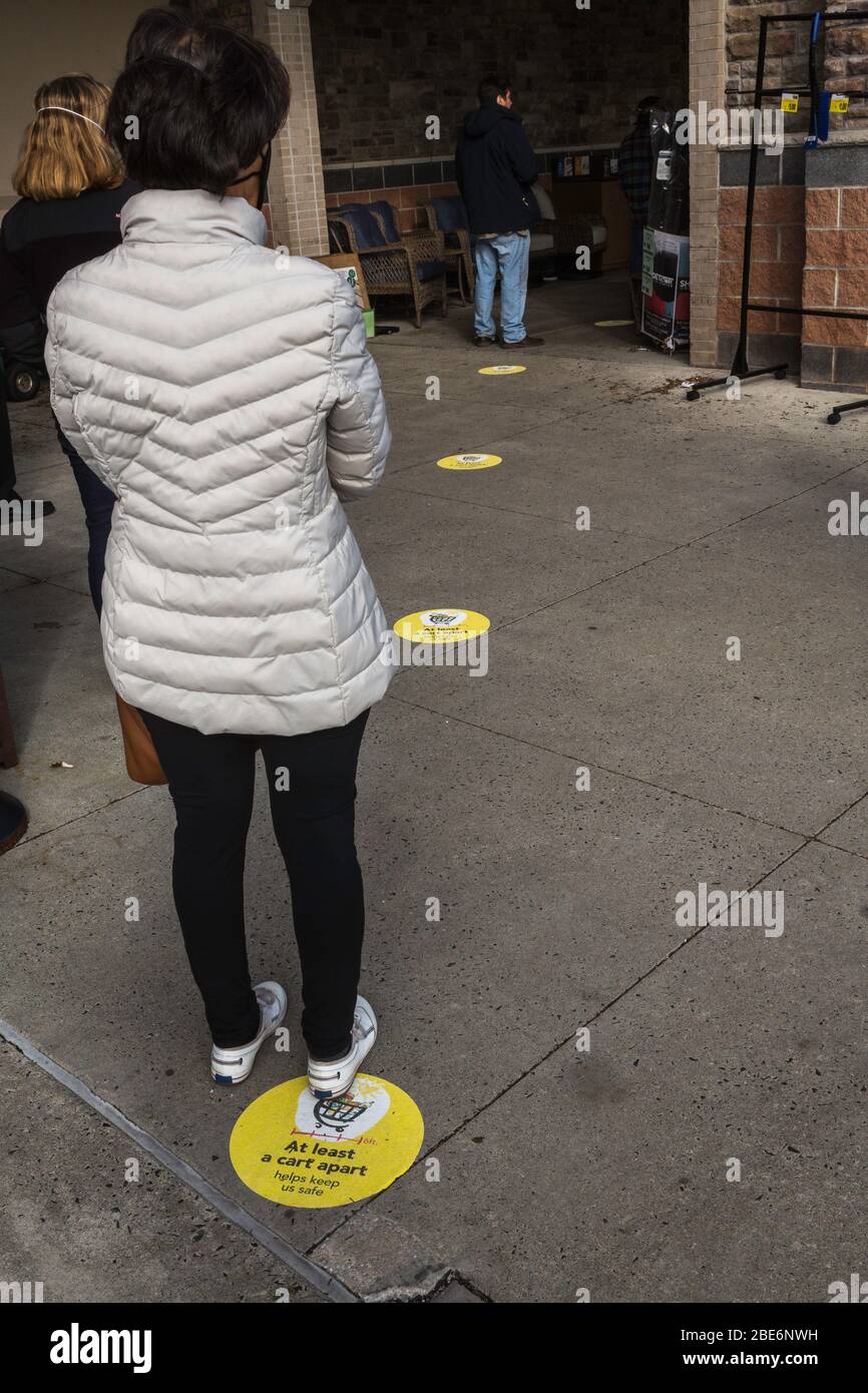 Covid-19, Menschen stehen auf Sicherheitsmarker warten in der Schlange, um Lebensmittel in Vorstadt Philadelphia, PA Supermarkt, 11. April 2020 zu kaufen Stockfoto