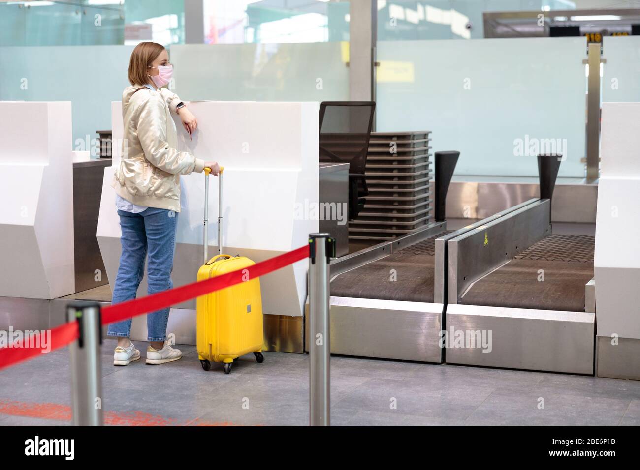 Frau mit Gepäck über Flugannullierung, steht an leeren Check-in-Schaltern am Flughafenterminal wegen Coronavirus-Pandemie/Covid-19-Ausbruch Trave Stockfoto