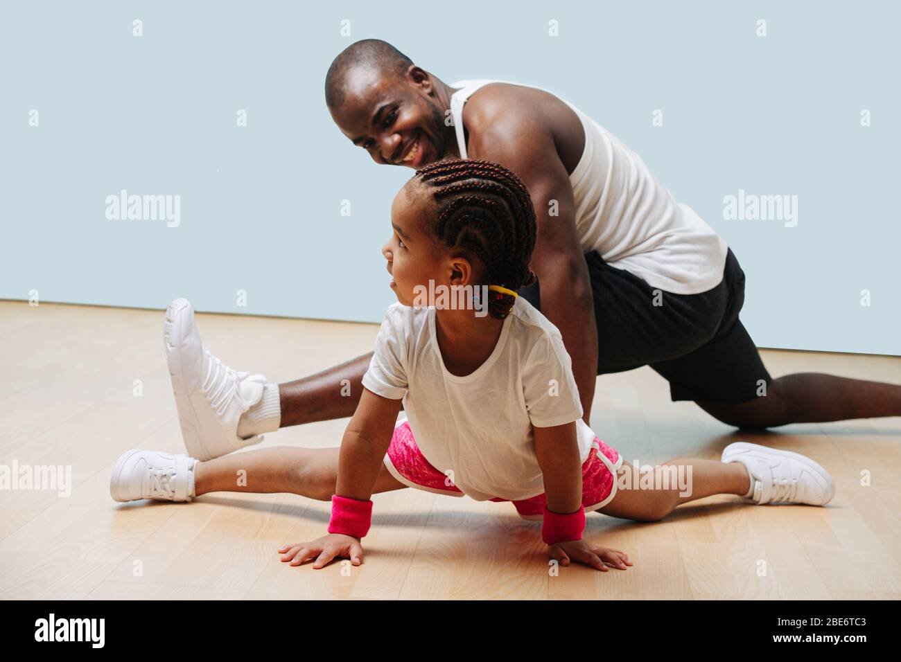 Vater und Tochter trainieren gemeinsam in Quarantäne und strecken ihre Beine Stockfoto