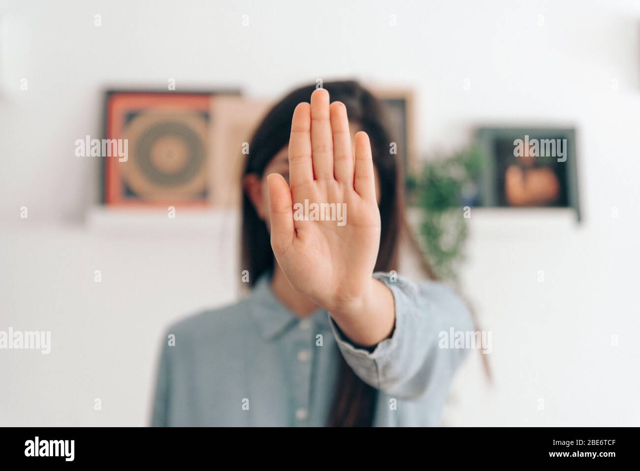 Coronavirus-Konzept. Mädchen in ihrem Haus sagt, Stop mit ihren Händen zu Coronavirus. Globaler Anruf, um zu Hause zu bleiben. Stockfoto