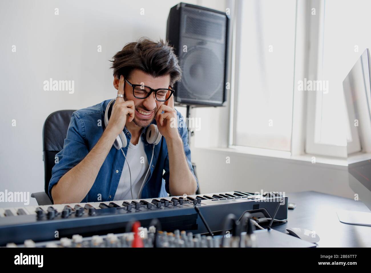 Der Mann wurde krank. Er hat einen Kopfschmerzen Komponist im Tonstudio. Musik-Produktionstechnik, . Man arbeitet an einem Tonmixer im Tonstudio Stockfoto