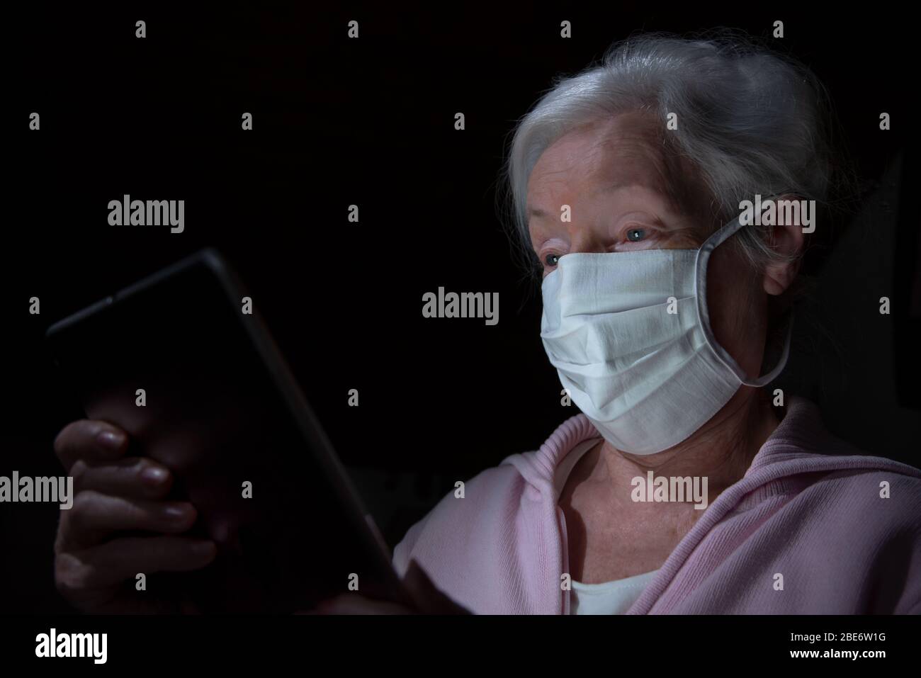 Ältere Frau mit Gesichtsmaske chats mit Tablet-Computer Stockfoto