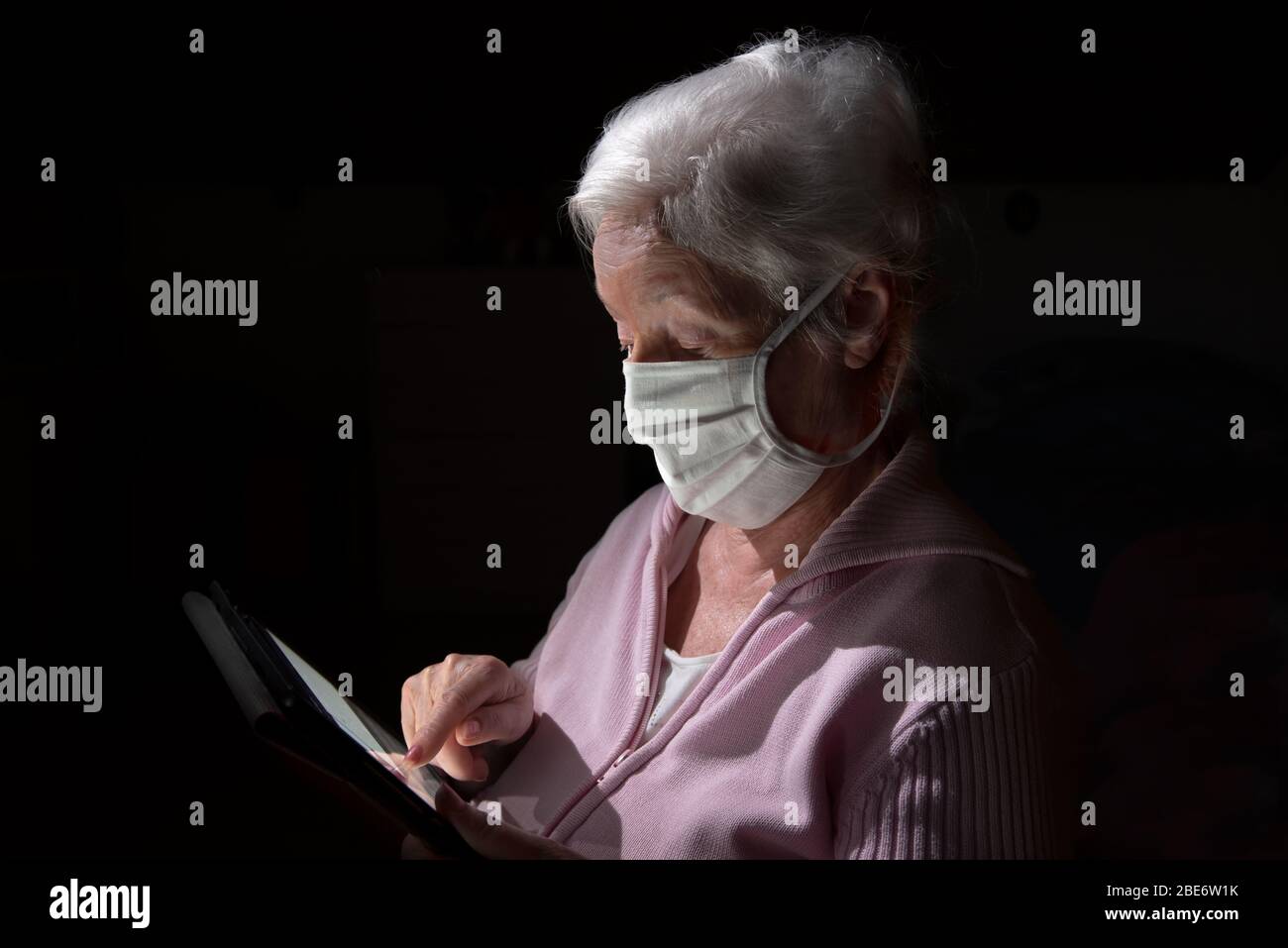 Ältere Frau mit Gesichtsmaske chats mit Tablet-Computer Stockfoto