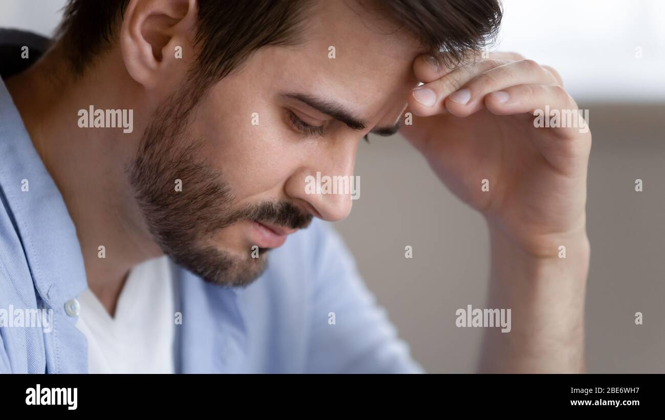 Frustrierter junger Mann, der die Stirn berührt und sich deprimiert fühlt. Stockfoto