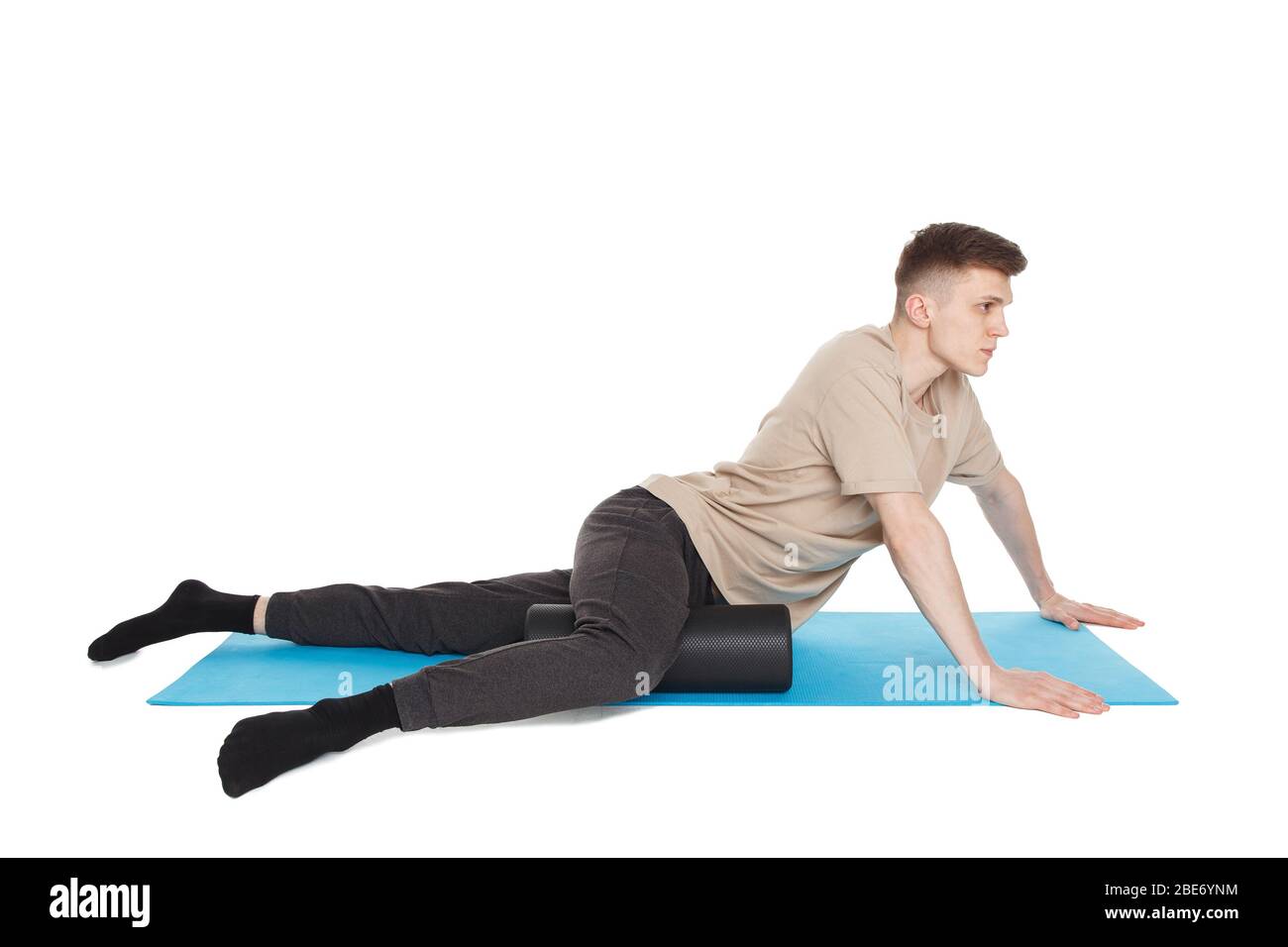 Der gutaussehende Mann zeigt Übungen mit einer Schaumstoffrolle für eine Myofaszialmassage von Triggerpunkten. Massage des inneren Oberschenkelmuskels. Isoliert auf WH Stockfoto