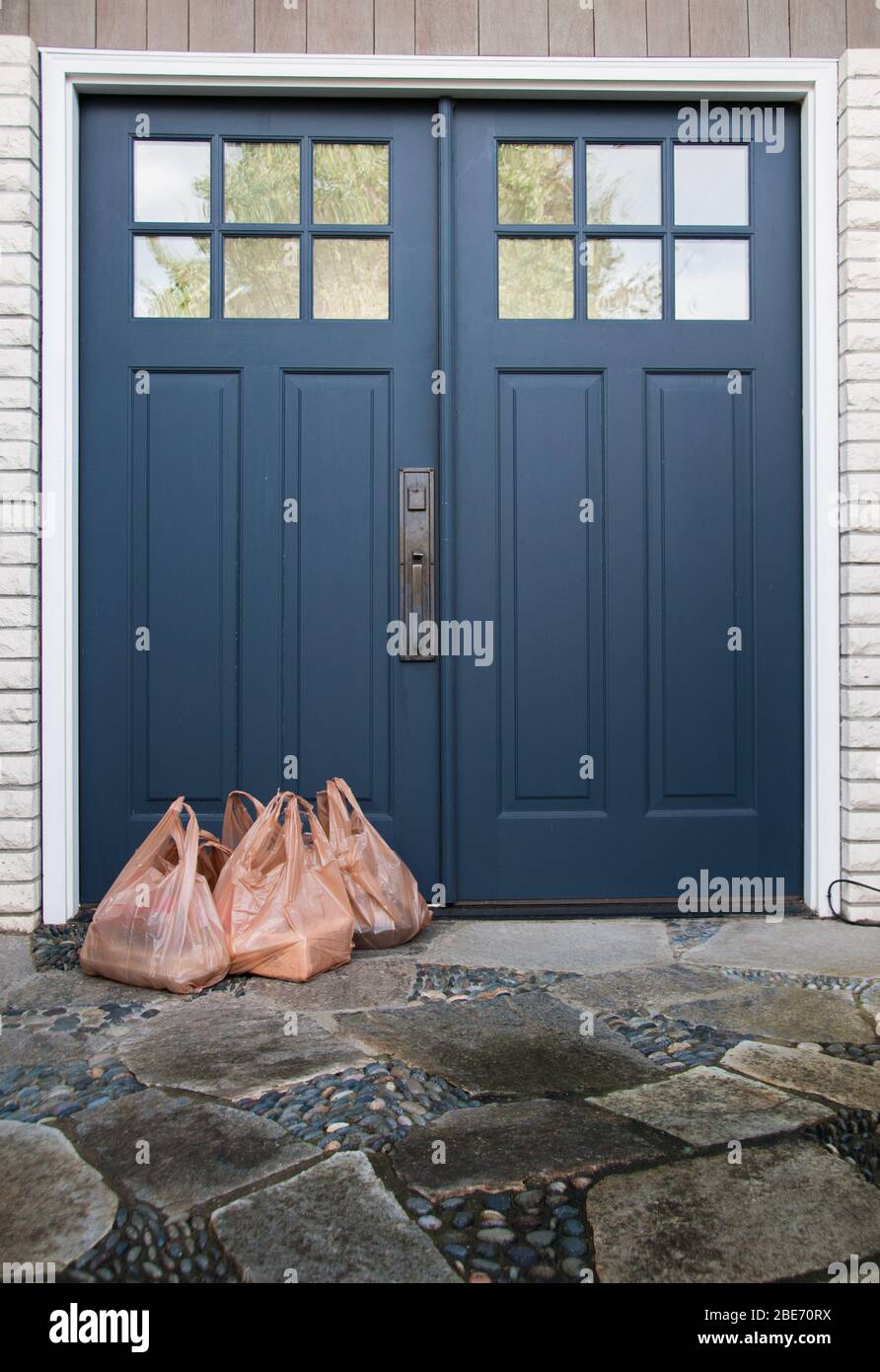 Kein Kontakt nach Hause Lieferung von Lebensmitteln Lebensmitteltaschen an der Haustür für Coronavirus COVID-19 Sicherheit links. Stockfoto