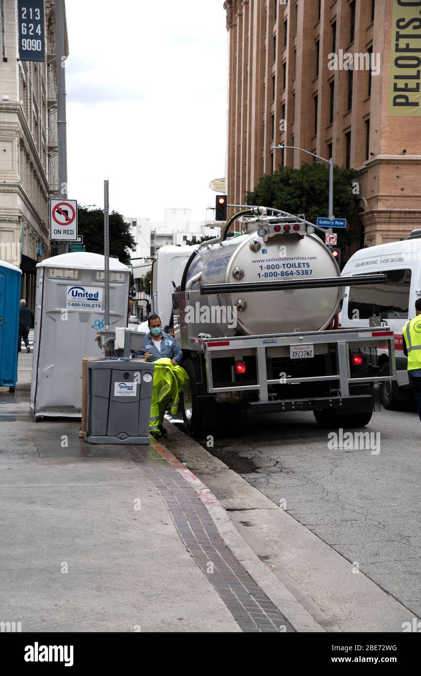 Los Angeles, CA/USA - 9. April 2020: Sanitärarbeiter reinigen tragbare Toiletten und Handwaschstationen, die für die Masse auf der Straße aufgestellt wurden Stockfoto