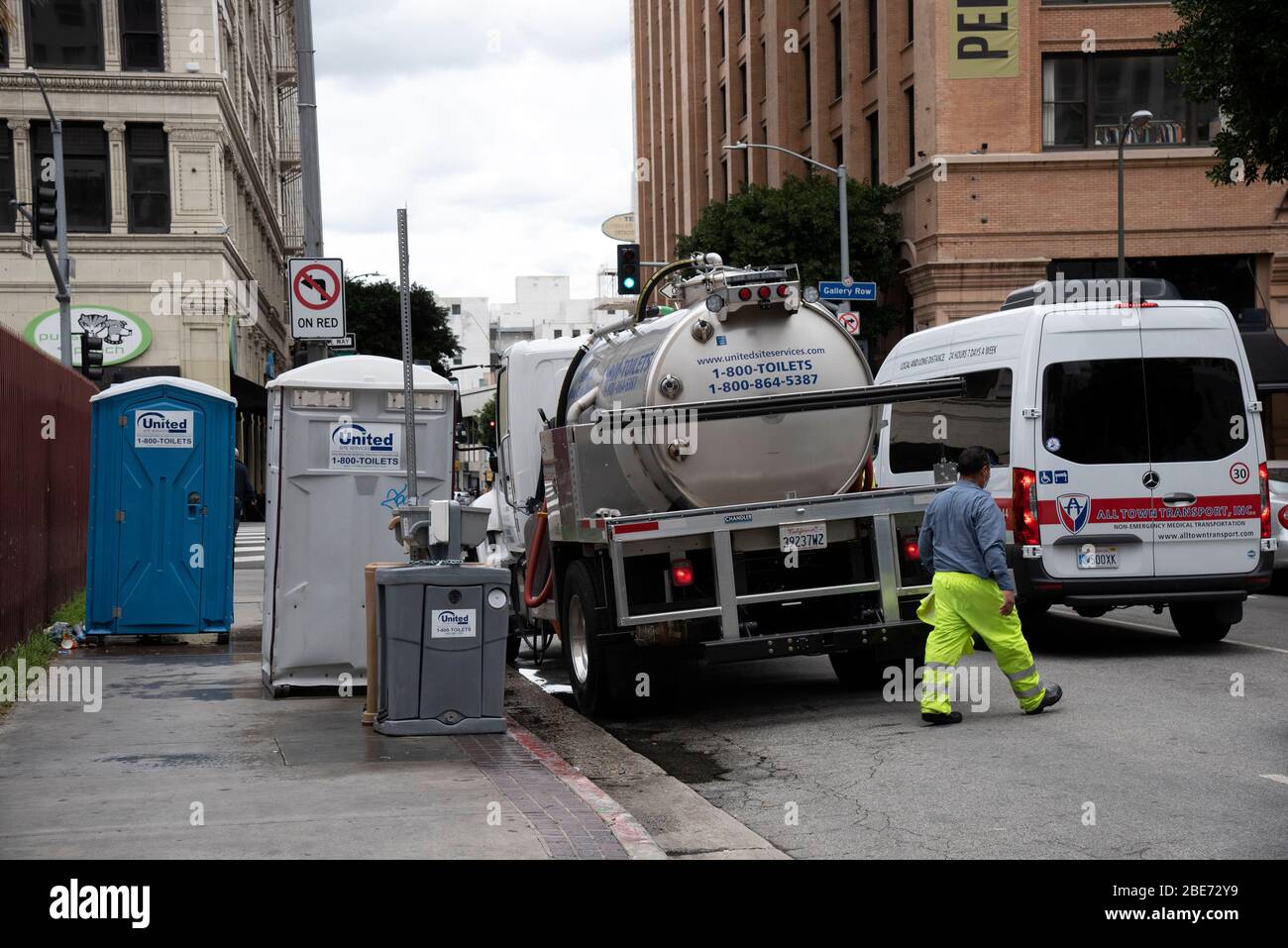 Los Angeles, CA/USA - 9. April 2020: Ein Krankenwagen fährt an Sanitäranlagen vorbei, die tragbare Toiletten und Handwaschstationen reinigen, die zur PR Stockfoto