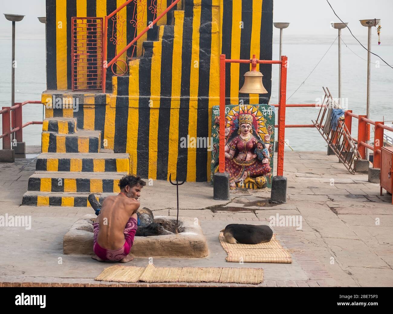 Ein junger Hindu sitzt vor einem improvisierten Straßenschrein von Ganesha in Varanasi Stockfoto