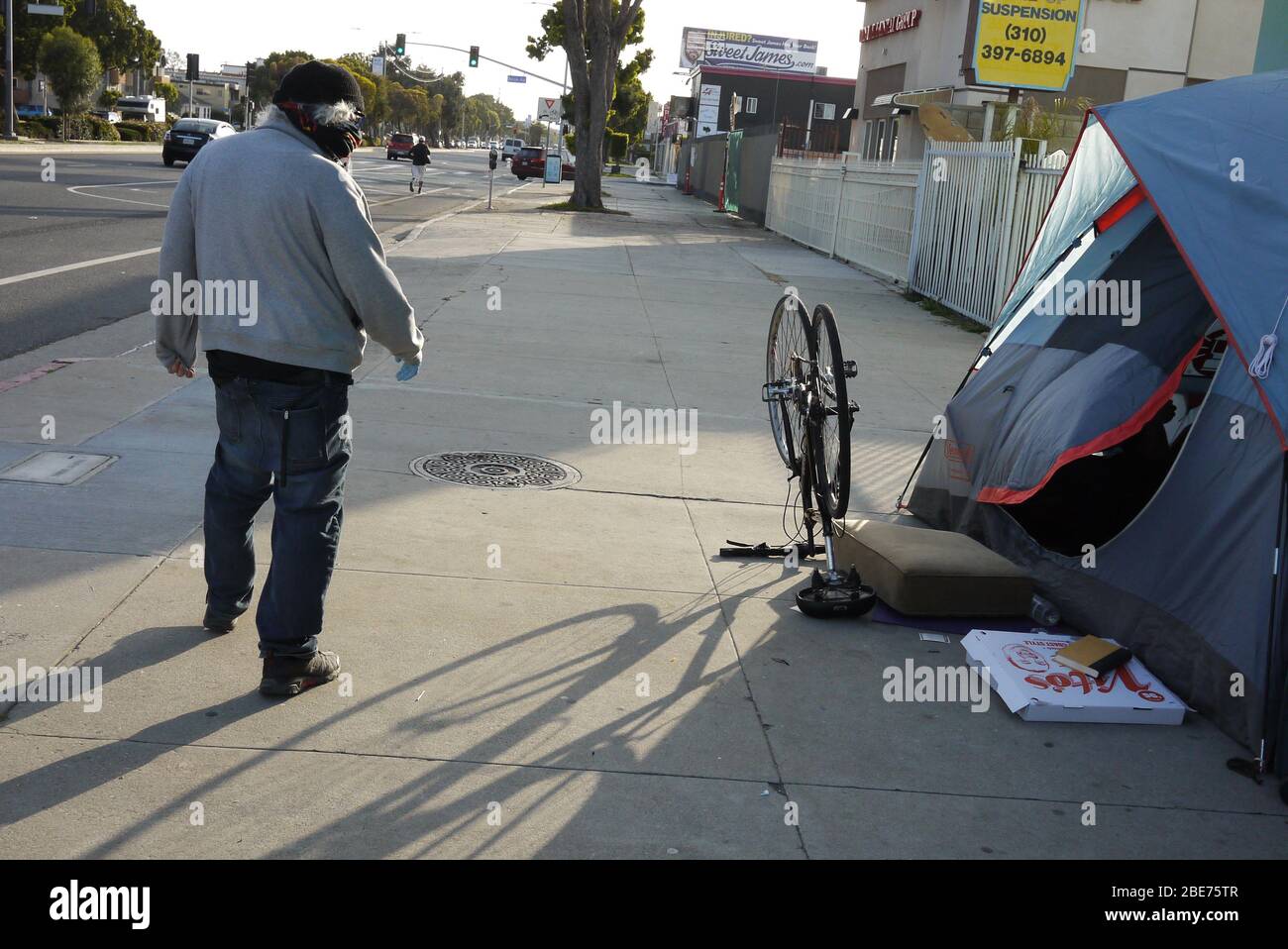 Mann in Bandanna geht an einem Bürgersteig obdachlosen Lager. Stockfoto