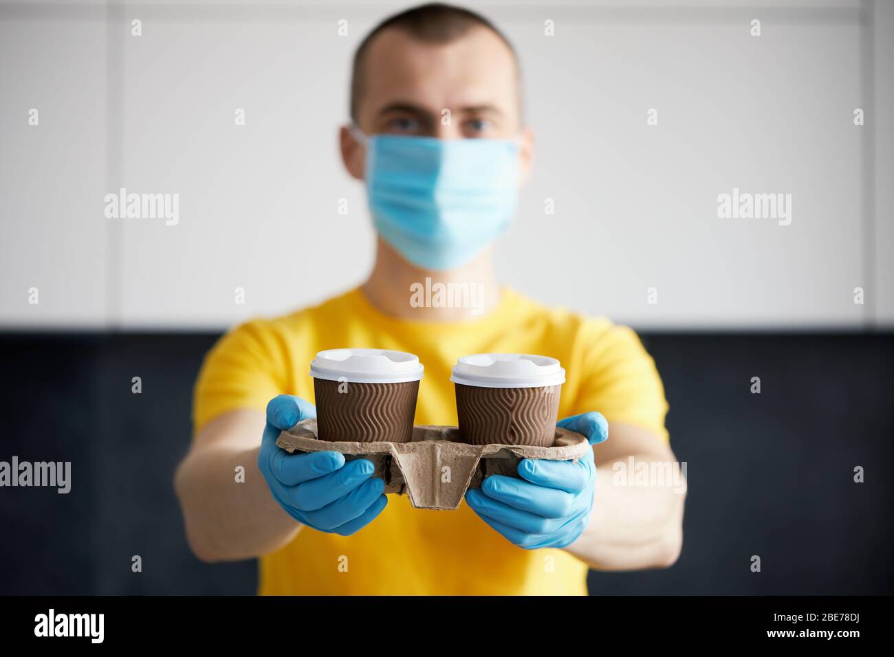 Kurier in Schutzmaske und medizinischen Handschuhen liefert Essen und Kaffee zum Mitnehmen. Lieferservice unter Quarantäne, Krankheitsausbruch, Coronavirus covi Stockfoto