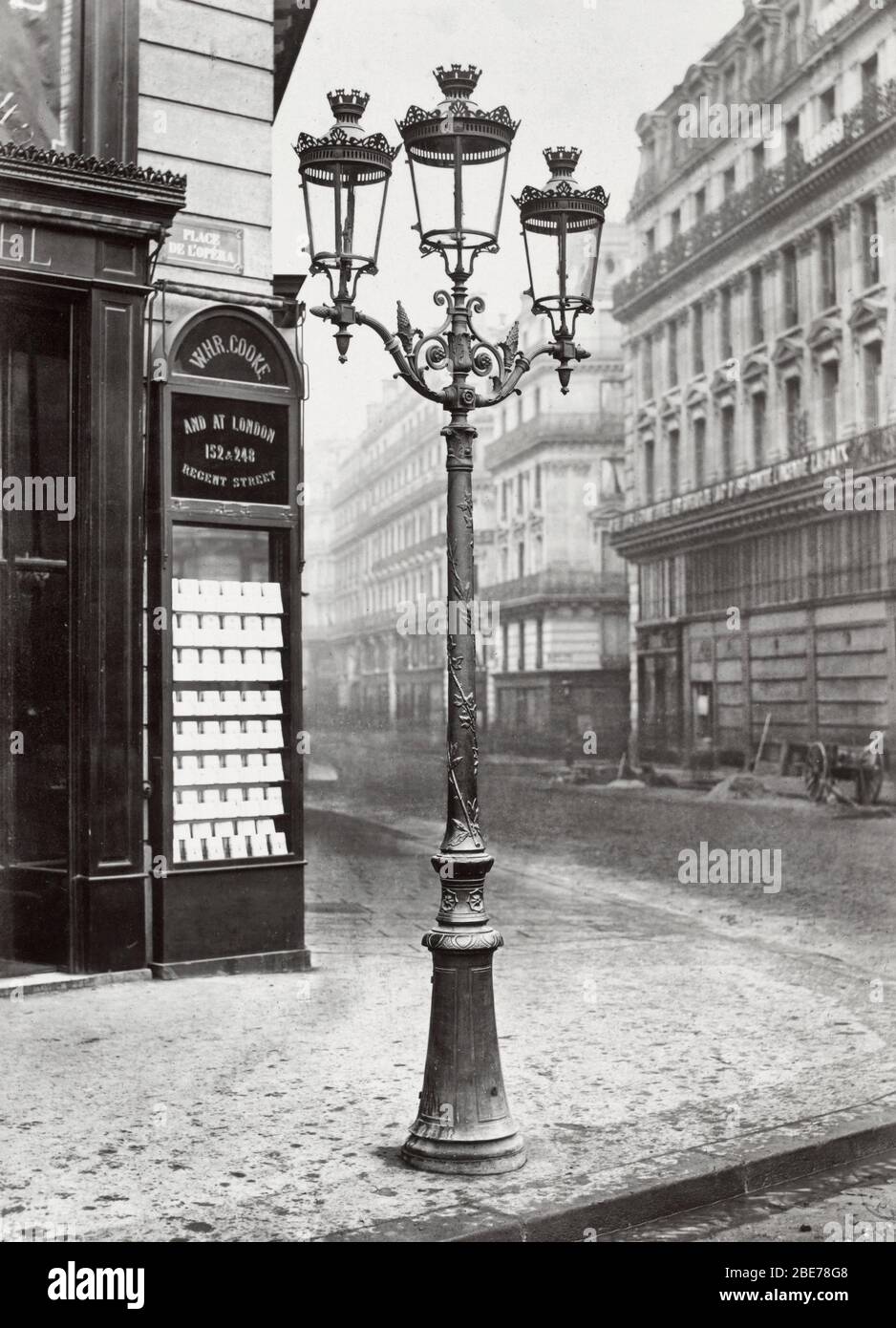 Place de l'Opéra. nr. 4- Oudry Stil Lampenständer mit drei Lampen an einer Straßenecke. Gebäude direkt hinter Lampenständer hat eine Plakette Lesung: WHR Cooke / und in London. 1878 Stockfoto
