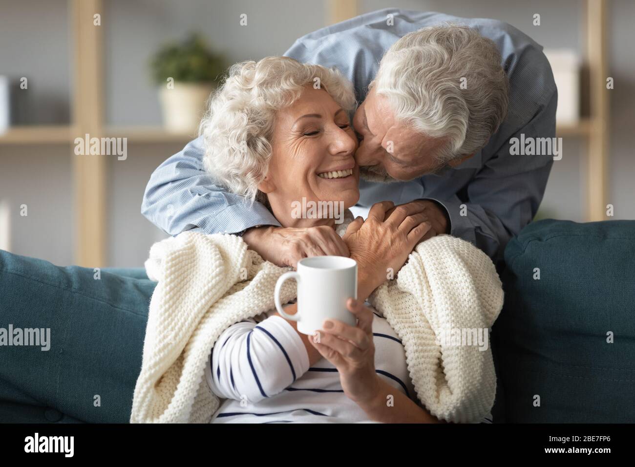 Loving älteren Mann küssen lächelnde Frau auf Wange Stockfoto