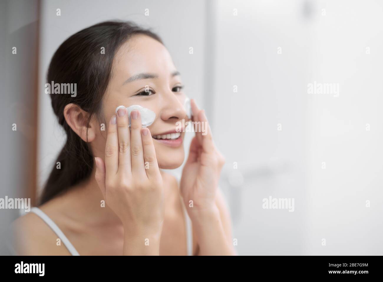 Junges Mädchen, das ihr Gesicht mit Seife wäscht. Stockfoto