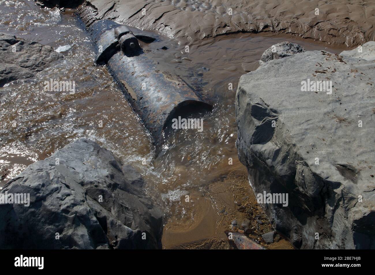 Alte Abschnitte des Abwasserrohrs zeigten sich nur bei außergewöhnlich niedrigen Gezeiten an einem lokalen Strand, der nun stillgelegt und der Natur überlassen wurde. Stockfoto