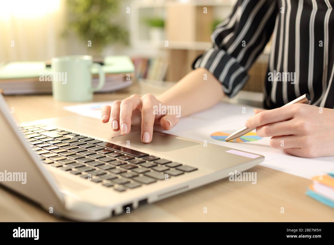 Nahaufnahme von Unternehmerhände Vergleich Graph Bericht auf Laptop auf dem Schreibtisch im Home Office Stockfoto