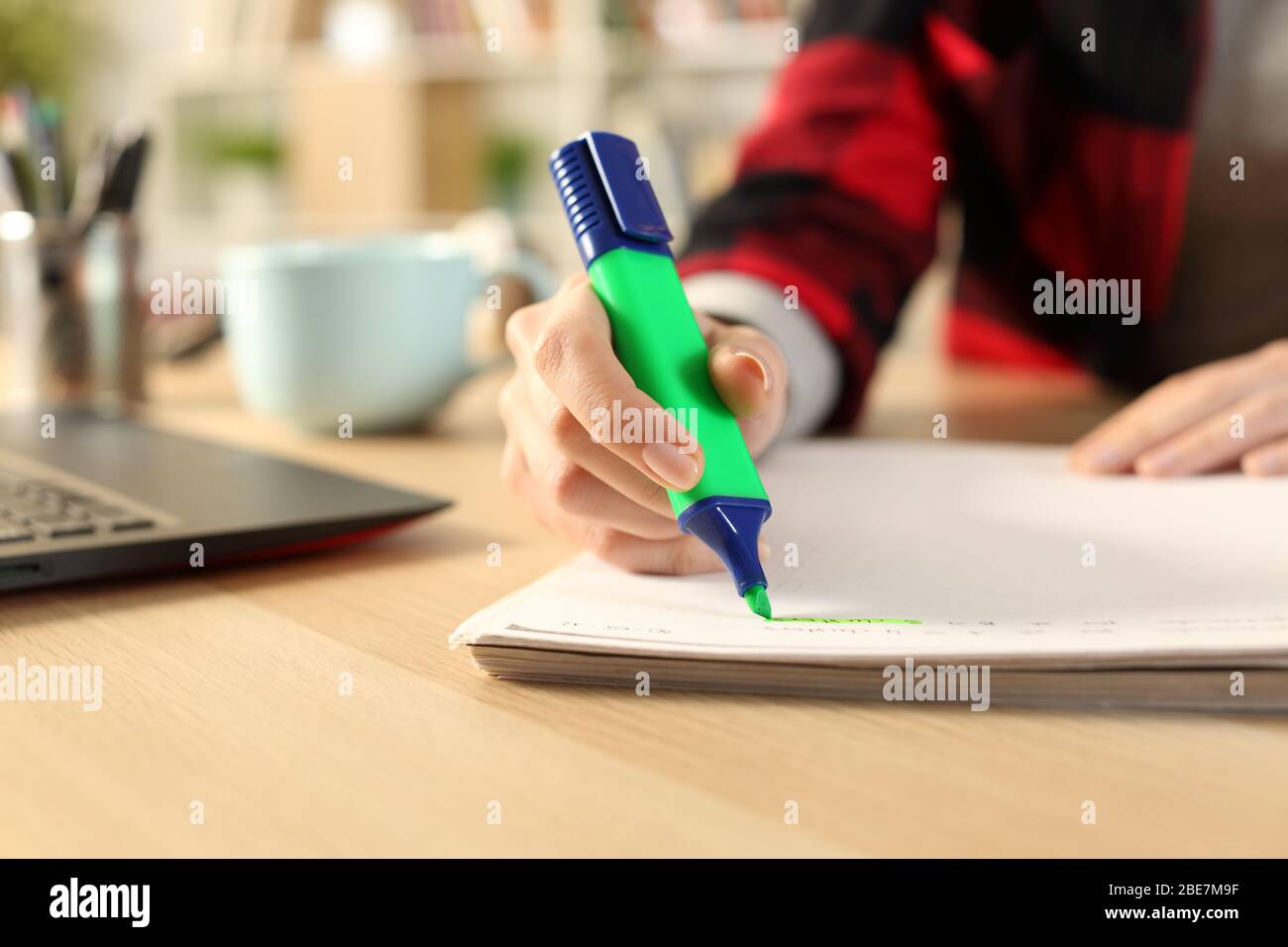 Nahaufnahme von Student Mädchen Hände mit grünen Textmarker Stift auf dem Notebook auf einem Schreibtisch zu Hause Stockfoto