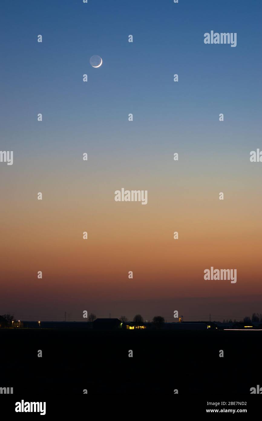 Farbenfroher Himmel in der Dämmerung mit kleinem Sichelmond Stockfoto