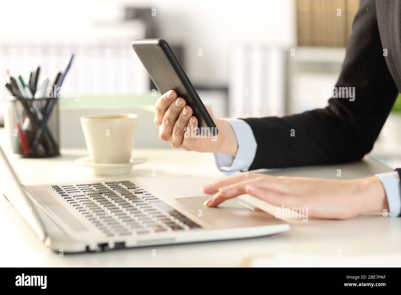 Nahaufnahme von Geschäftsfrau Hände mit mehreren Geräten sitzen auf einem Schreibtisch im Büro Stockfoto