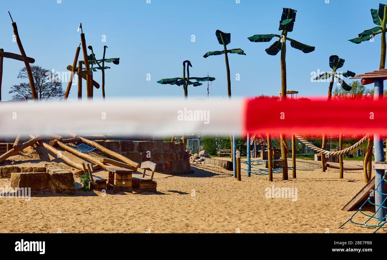 Rot-weiße Flutterband vor einem Abenteuerspielplatz in Deutschland, der wegen Corona geschlossen ist, Konzeptfoto der Covid 19-Abschaltung Stockfoto