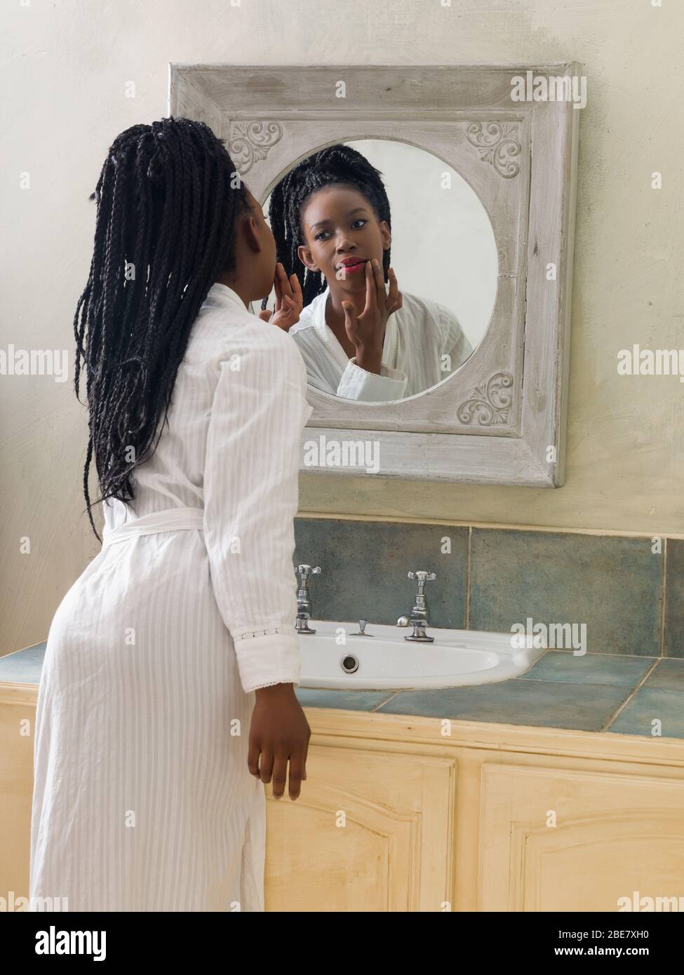 Hübsche junge afrikanische amerikanische Frau, die Ihre morgendliche Routine zu tun vor dem Badezimmerspiegel Stockfoto
