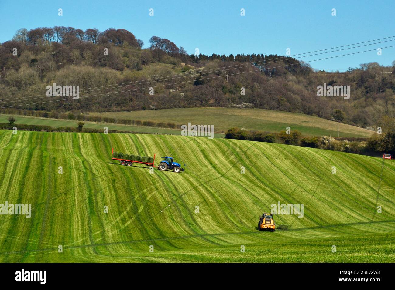 Traktoren, die Heuschreckenhajlage auf Feldern außerhalb von Princes Risborough, Buckinghamshire, Großbritannien, ernten Stockfoto