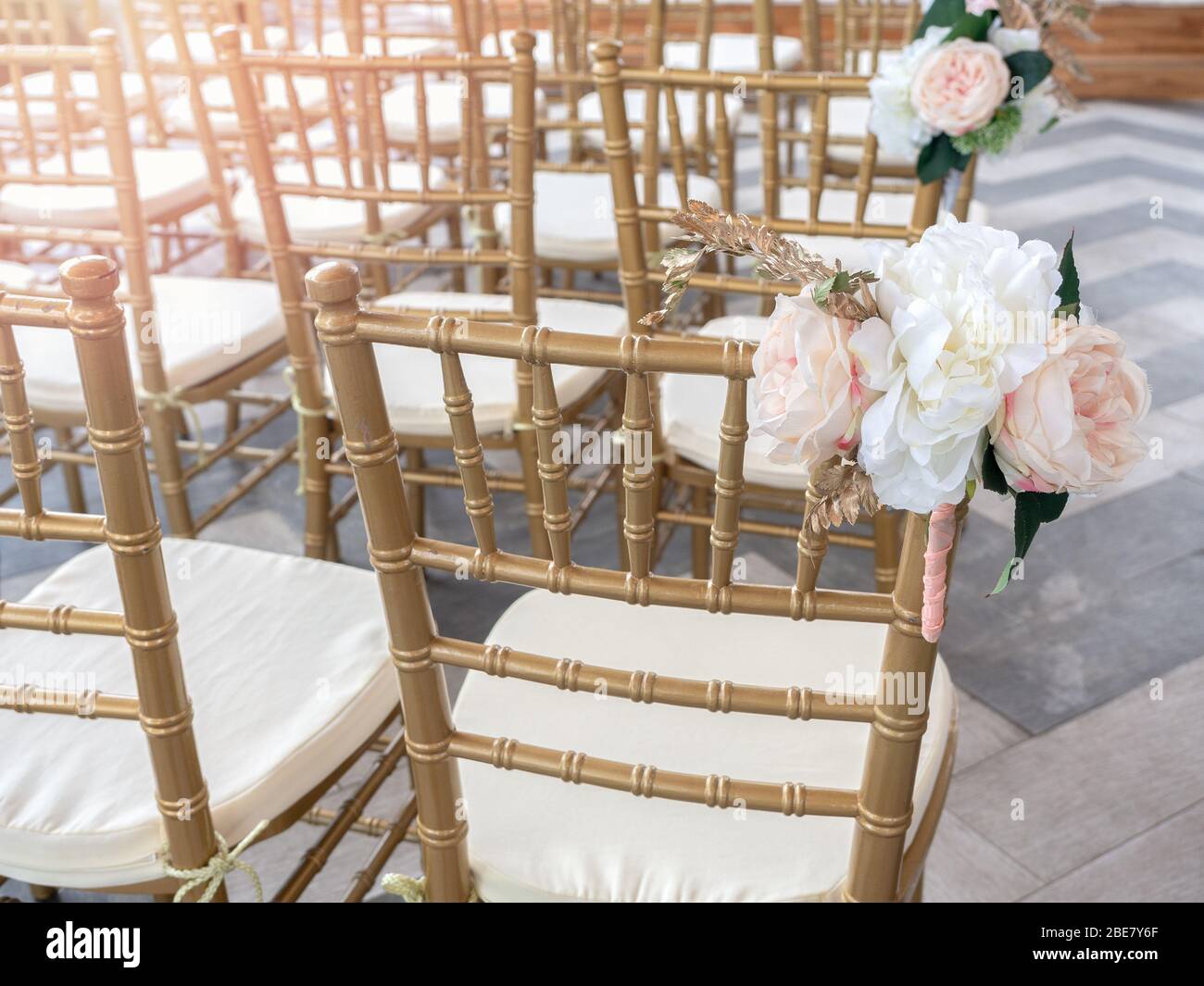 Hochzeitsstühle dekorieren mit schönen Blumen für Hochzeitszeremonie. Hochzeitsfeier mit goldenen Stühlen. Stockfoto