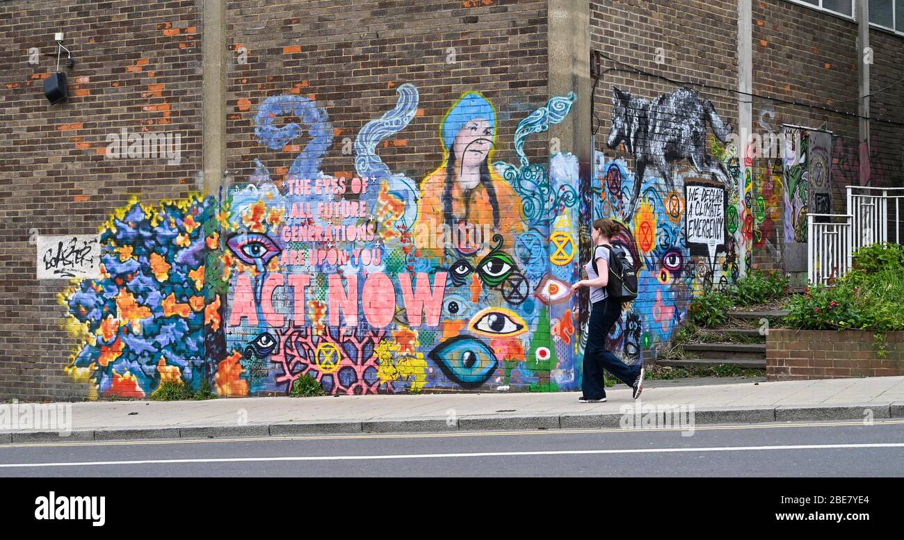Brighton UK 13. April 2020 - EINE Frau geht an einem kalten, langweiligen Osterfeiertagsmontag an einem Klimamontage vorbei, auf dem ein Bild von Greta Thunberg in Brighton zu sehen ist, während die Regierungen die Beschränkungen in ganz Großbritannien weiterhin sperren. Quelle: Simon Dack / Alamy Live News Stockfoto