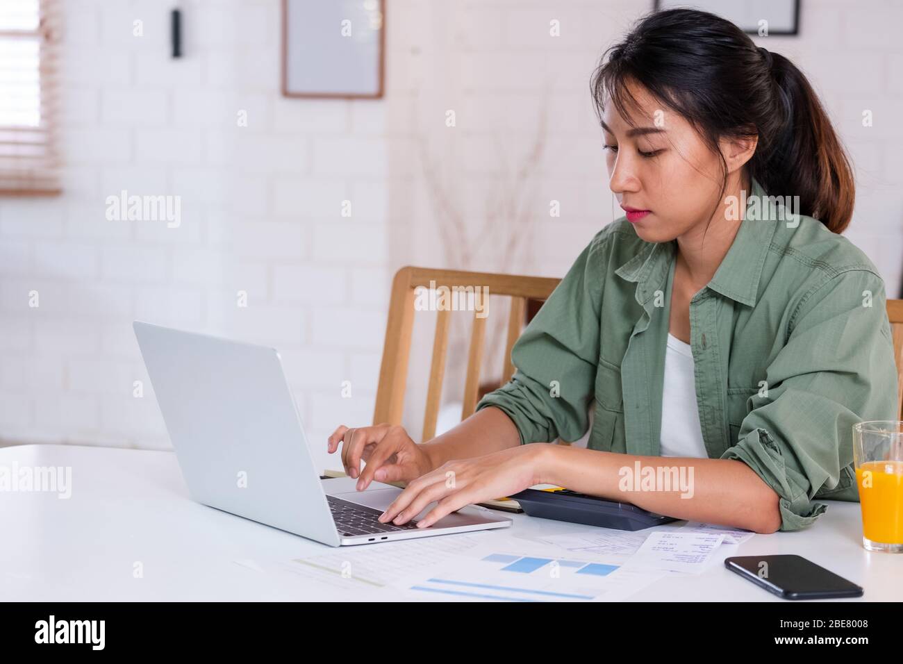 Asiatische Frau verwenden Laptop und Rechner berechnen Arbeitsprojekt Budget in der Küche zu Hause Stockfoto