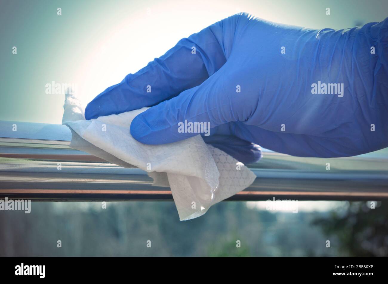 Desinfektion von Oberflächen an öffentlichen Orten - Hand in Einweg-Handschuh Reinigung eines Handlaufs Stockfoto