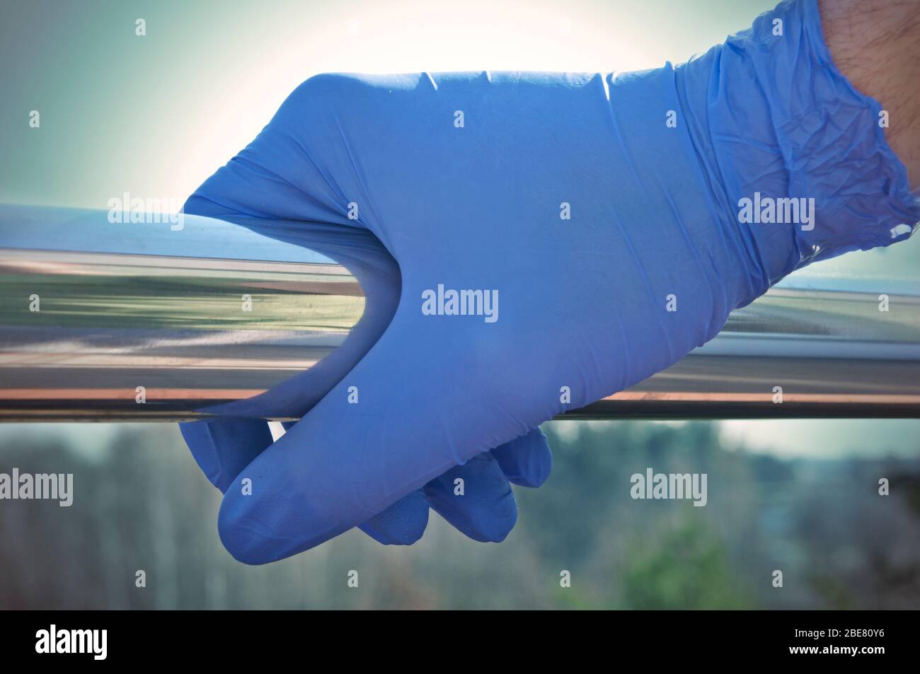 Hand in Einweg-Handschuh auf einem Handlauf an einem öffentlichen Ort - Pandemie Vorsorge Stockfoto