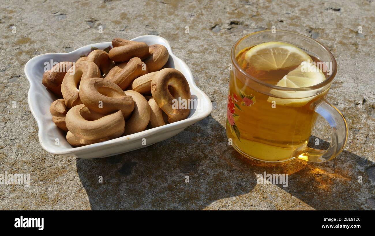 Heißer Tee in einer Glasschale. Neben dem Becher liegt ein Teller mit Bagels. Stockfoto