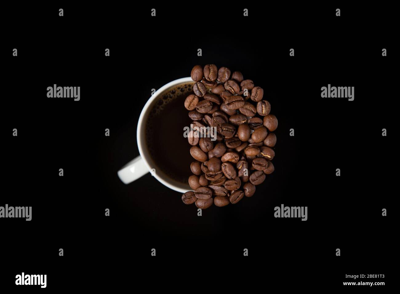 Kaffeebohnen im Halbkreis über Kaffeetasse isoliert auf schwarzem Hintergrund Stockfoto