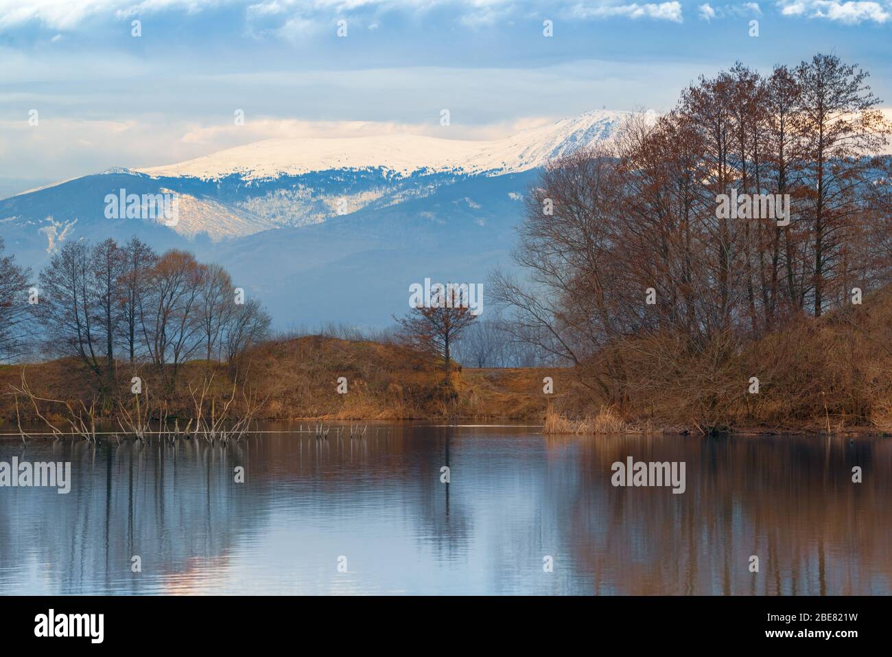 Schöne Seenlandschaft mit Spiegelung von Bäumen im Wasser vor einem schneebedeckten Berghintergrund Stockfoto