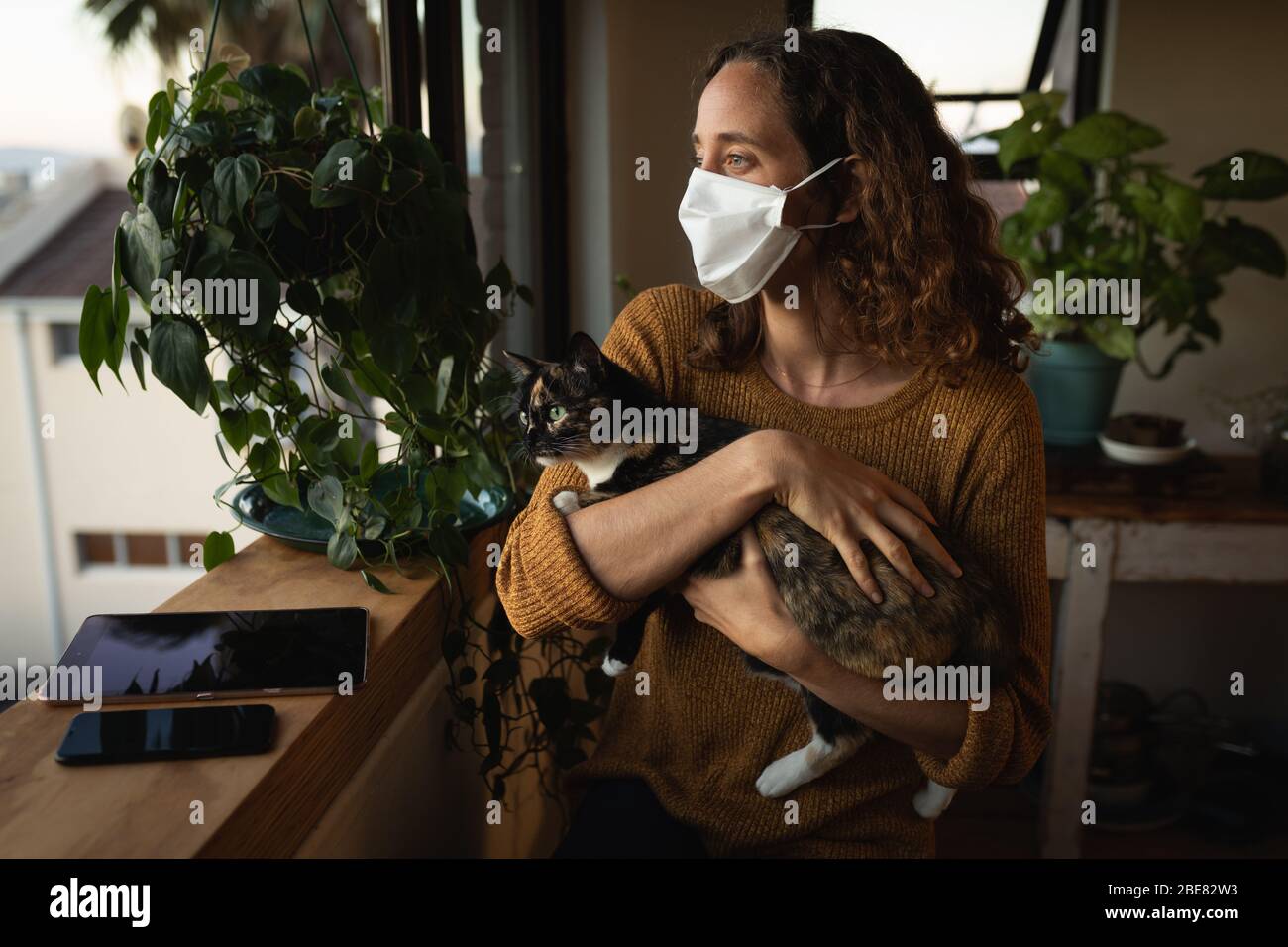 Frau, die zu Hause eine Gesichtsmaske trägt. Soziale Distanzierung in der Quarantäne während der Coronavirus-Epidemie Stockfoto