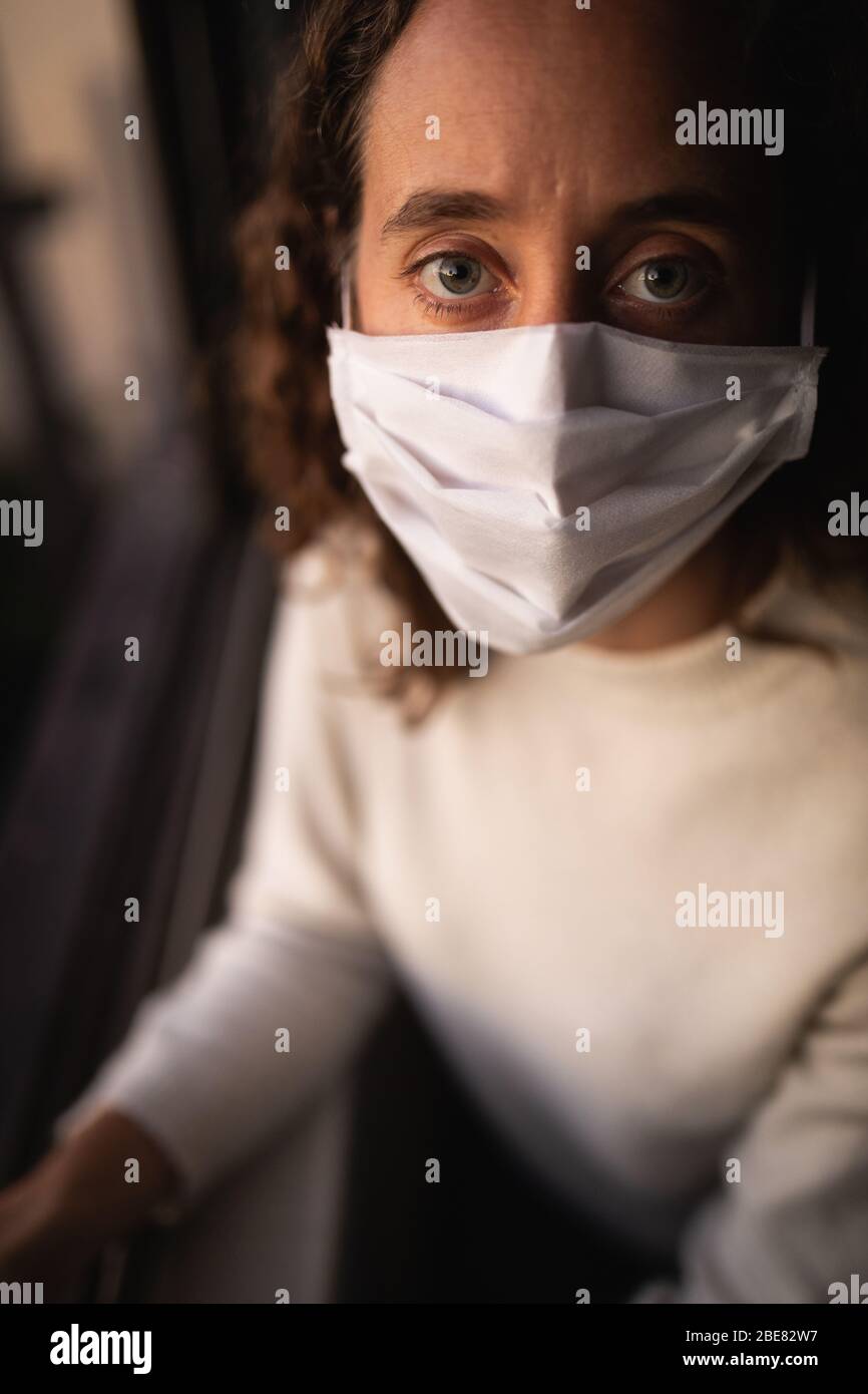 Frau, die zu Hause eine Gesichtsmaske trägt. Soziale Distanzierung in der Quarantäne während der Coronavirus-Epidemie Stockfoto